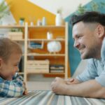 Father and young son lying on the floor talking