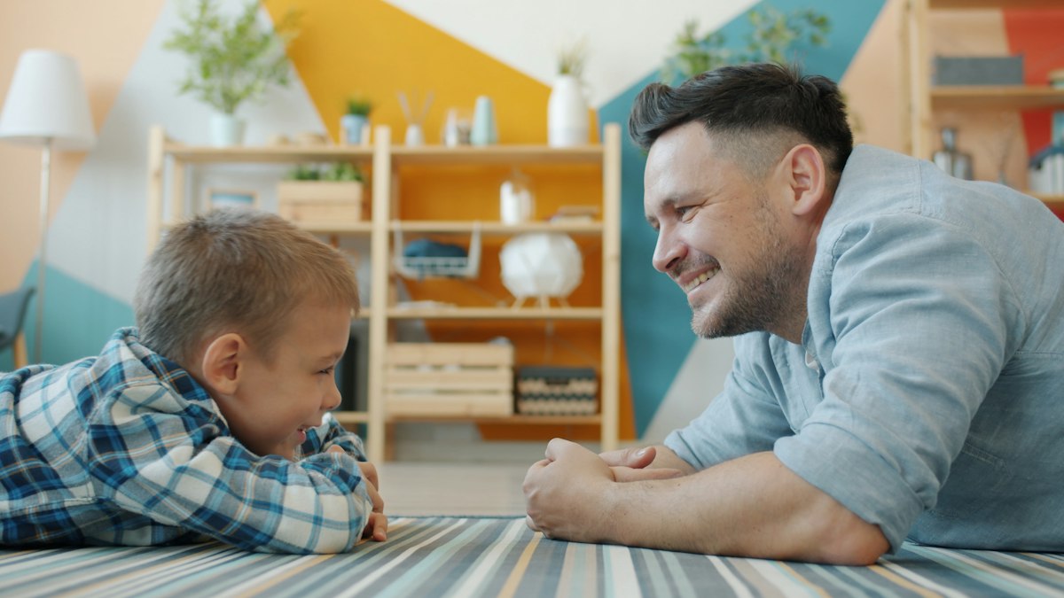 Father and young son lying on the floor talking